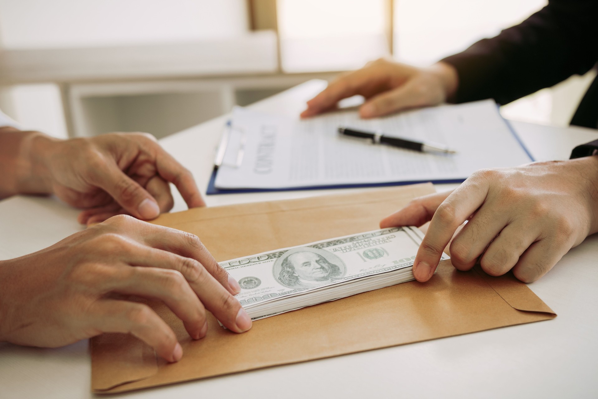Partner has made a fraud in the contract of sale and being handed a cash and pen to the businessman signing the contract corruption bribery concept.